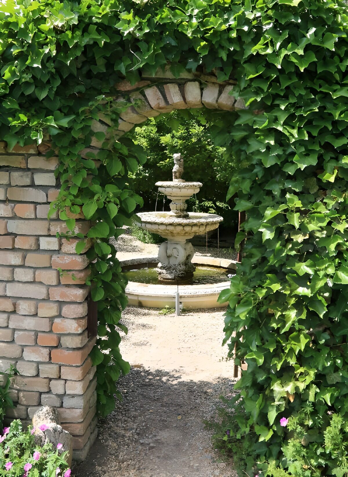 Gartenbrunnen im efeugrünen Ziegelbogen