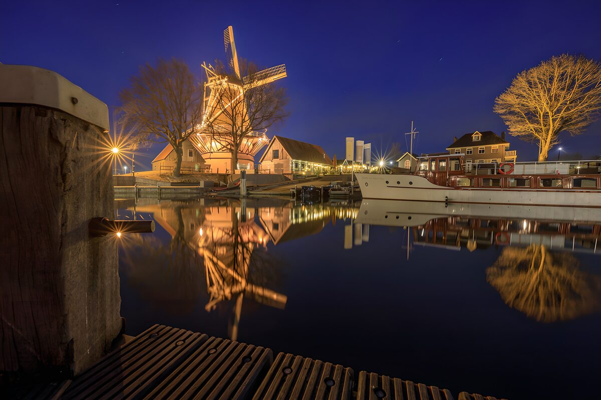 Beleuchtete Windmühle am nächtlichen Hafen