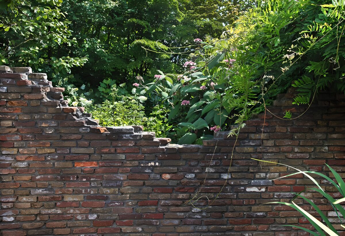 Alte Ziegelmauer im üppigen Gartengrün