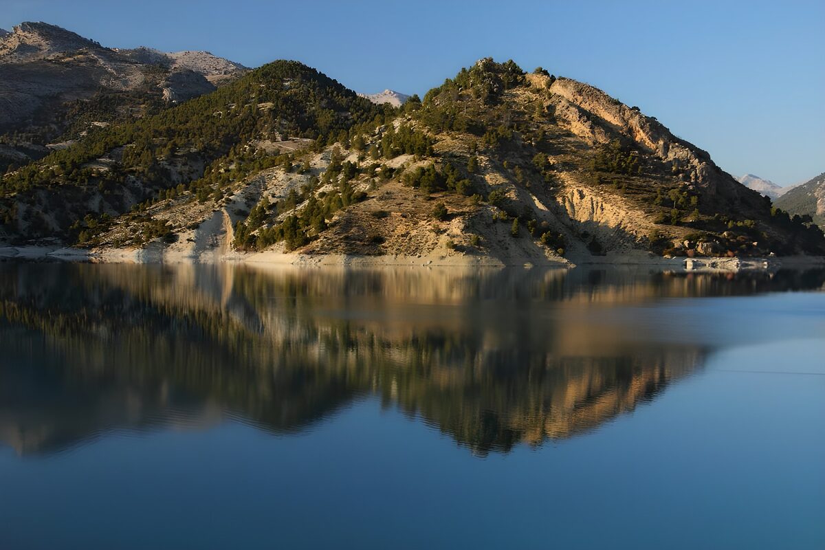 Blauer Bergsee unter sonnigen Felswänden