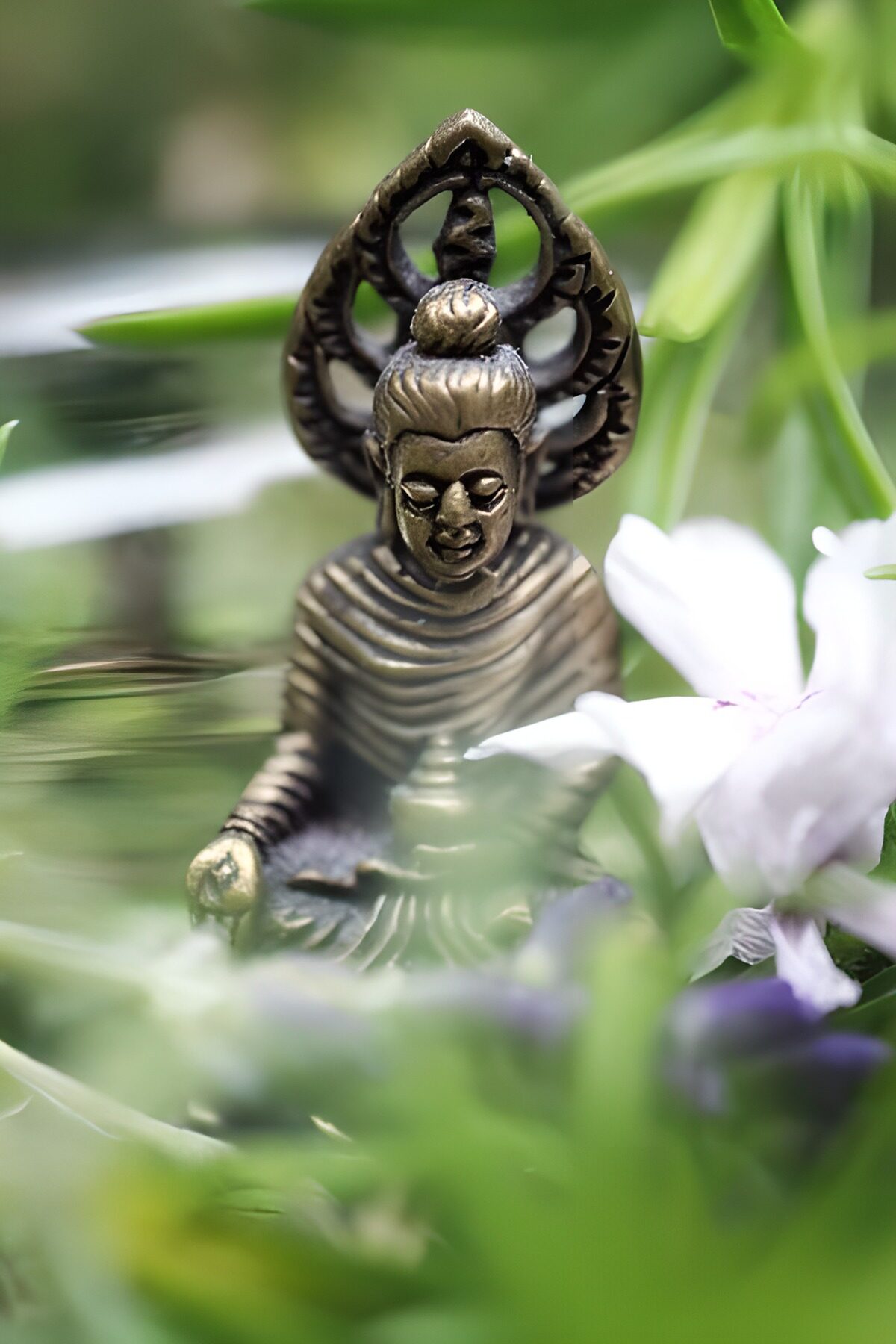 Bronzefarbener Buddha neben weißer Blüte