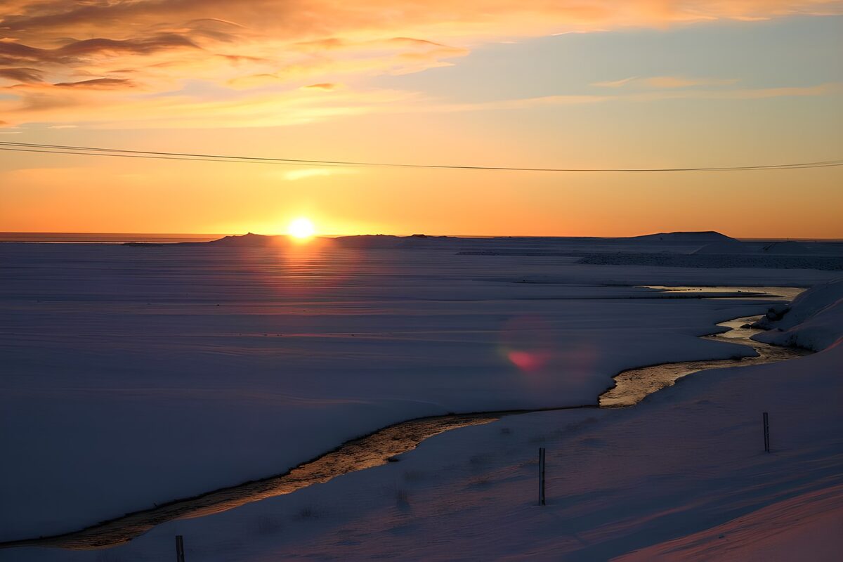 Sonnenuntergang am verschneiten Wasserlauf
