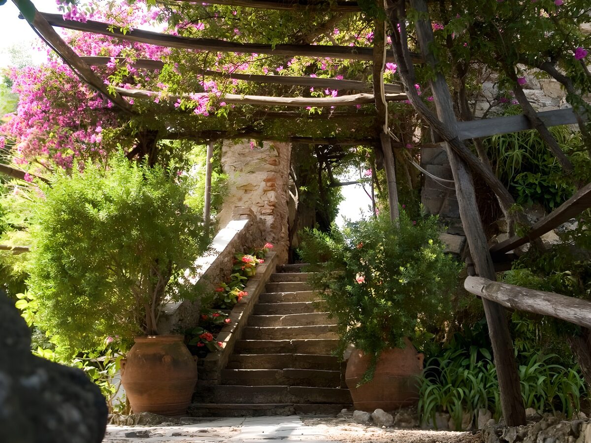 Steintreppe unter blühender Pergola
