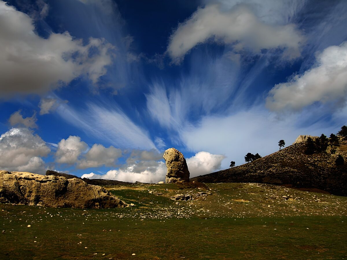Felsen und Gras unter weitem Wolkenhimmel