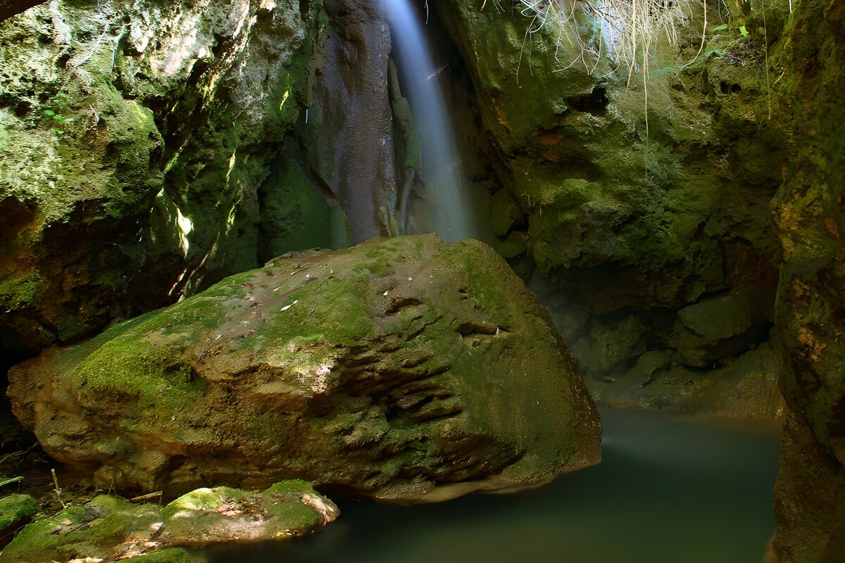 Schmaler Wasserfall zwischen moosgrünen Felsen