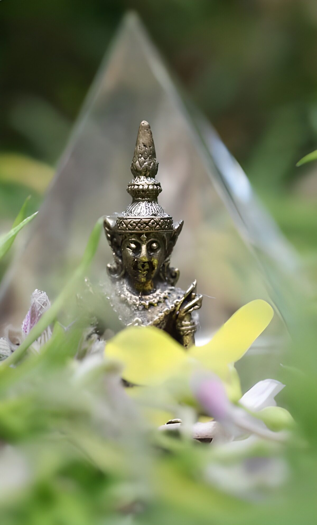 Bronzefigur zwischen Blüten und Blättern